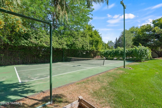 view of tennis court with fence and a lawn