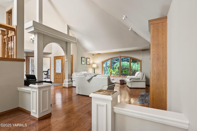 living room featuring wood finished floors, baseboards, and high vaulted ceiling