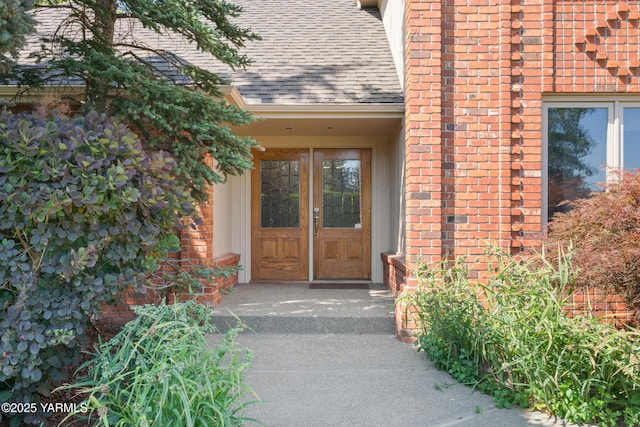 doorway to property with brick siding, french doors, and roof with shingles