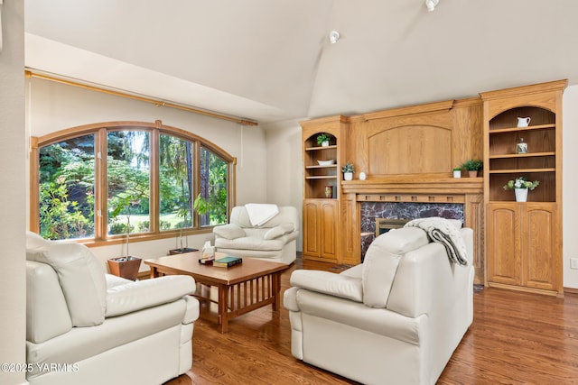 living room featuring high vaulted ceiling, light wood-style floors, and a fireplace