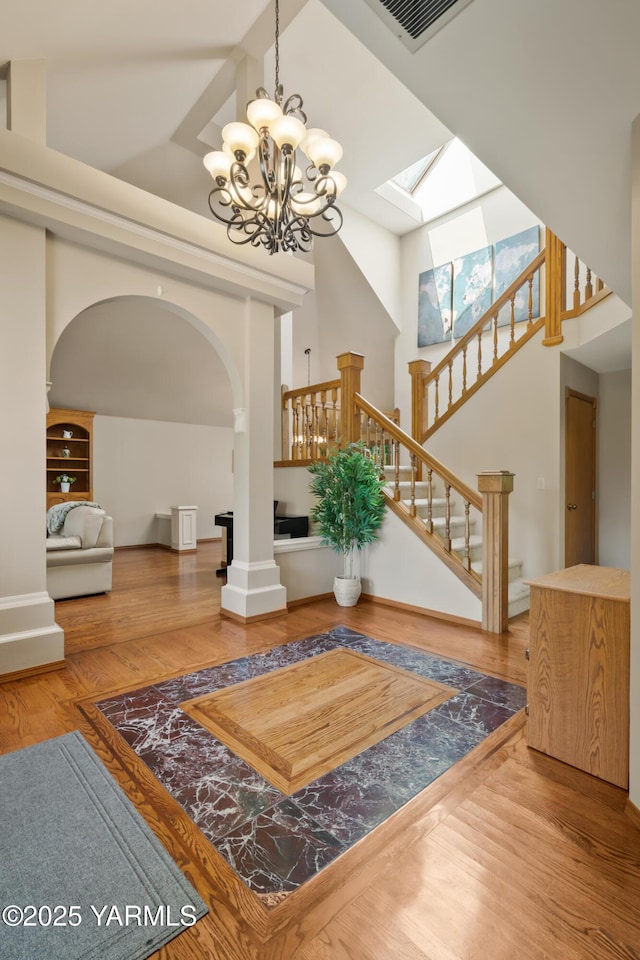 entryway featuring visible vents, wood finished floors, stairway, arched walkways, and a high ceiling