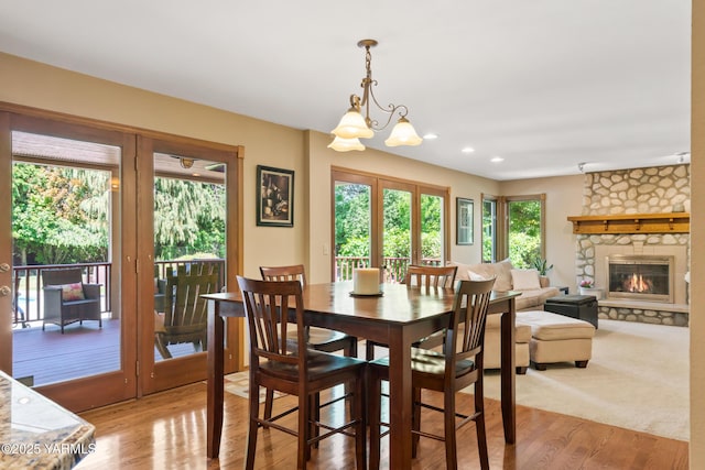 dining area featuring a stone fireplace, an inviting chandelier, recessed lighting, and wood finished floors