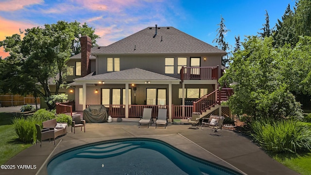 rear view of property with stairway, a fenced in pool, a chimney, a shingled roof, and a patio area