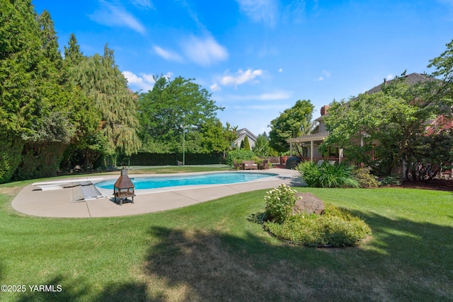 pool with a patio area, a lawn, and a diving board