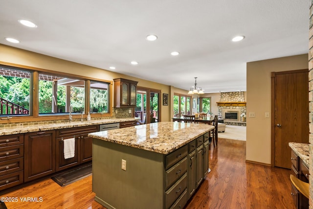 kitchen featuring dark wood-style flooring, backsplash, a kitchen island, and a sink