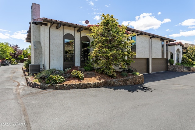 24 Crest Cir, Yakima, WA 98908 - view of side of property featuring an attached garage, driveway, a chimney, a tile roof, and stucco siding