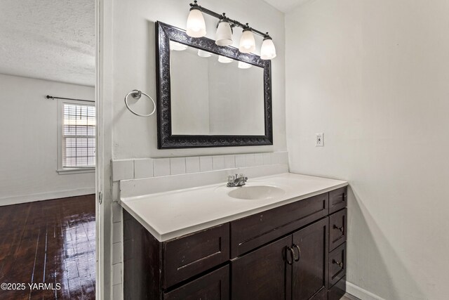 bathroom featuring baseboards, vanity, a textured ceiling, and wood finished floors