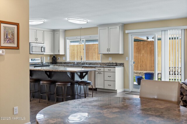 5910 W Lincoln Ave Unit 36, Yakima, WA 98908 - kitchen featuring stainless steel appliances, a breakfast bar area, a sink, white cabinets, and dark wood-style flooring