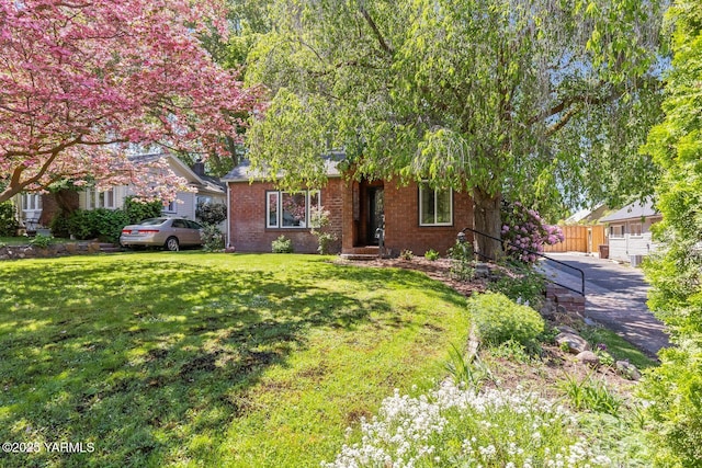 view of front of property featuring brick siding, fence, and a front yard