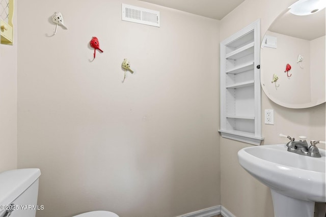 half bath featuring toilet, visible vents, and a sink