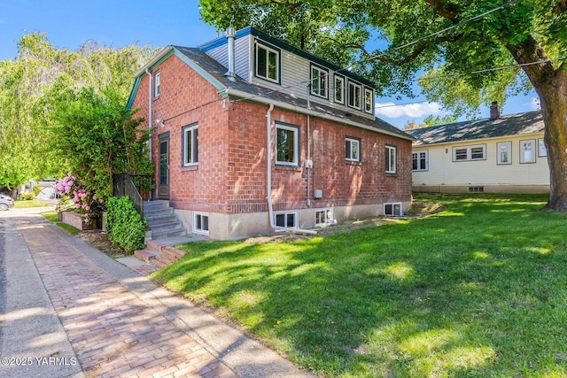 view of home's exterior featuring a lawn, brick siding, and a shingled roof