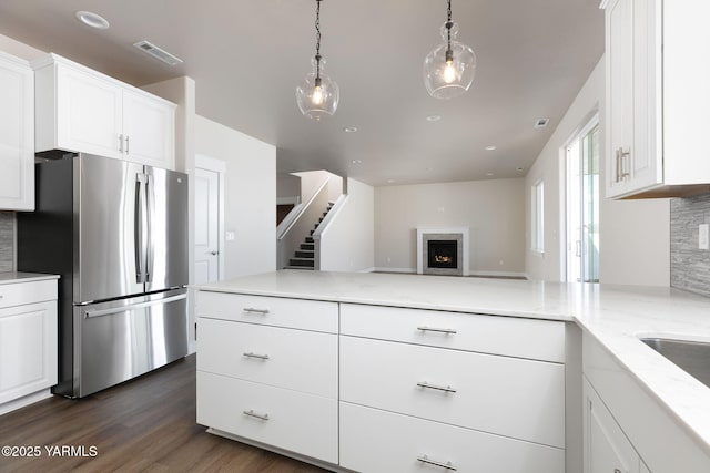 kitchen featuring tasteful backsplash, visible vents, dark wood-style floors, light stone counters, and freestanding refrigerator