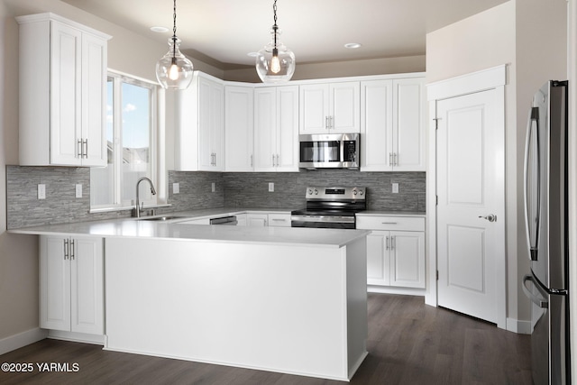 kitchen featuring stainless steel appliances, light countertops, a sink, and a peninsula