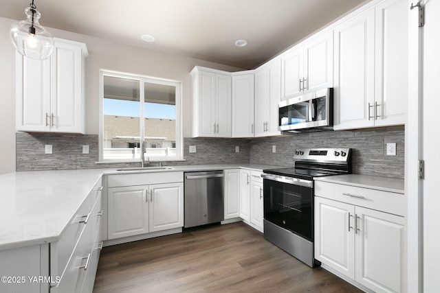 kitchen featuring tasteful backsplash, white cabinets, appliances with stainless steel finishes, dark wood-type flooring, and a sink