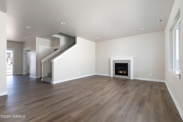 unfurnished living room with a fireplace, visible vents, stairway, dark wood-type flooring, and baseboards