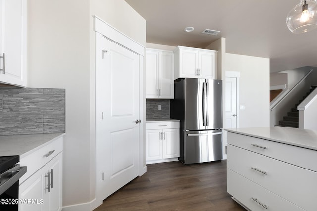 kitchen featuring visible vents, dark wood-type flooring, freestanding refrigerator, and white cabinets