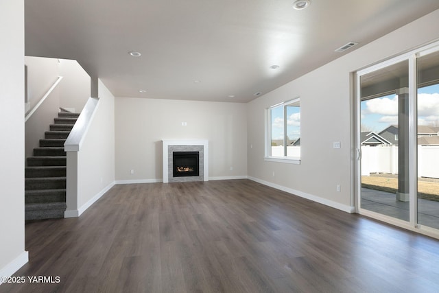 unfurnished living room with dark wood-style floors, a fireplace, stairs, and baseboards