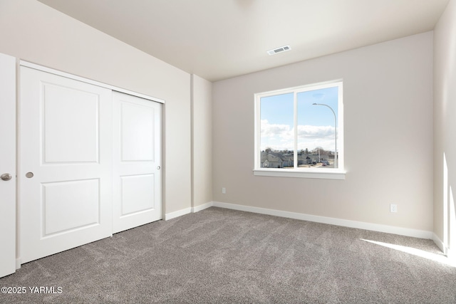 unfurnished bedroom with a closet, carpet, visible vents, and baseboards