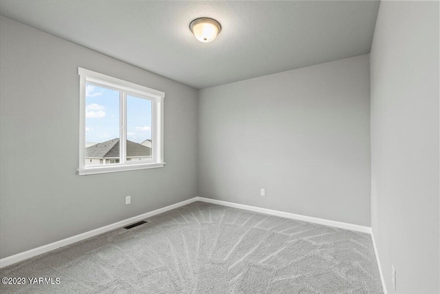 carpeted spare room with visible vents and baseboards