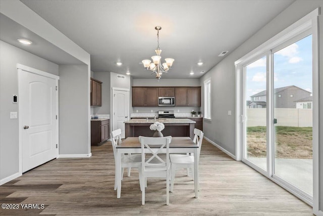 dining space with baseboards, visible vents, a chandelier, and wood finished floors