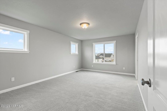 unfurnished room with light carpet and baseboards