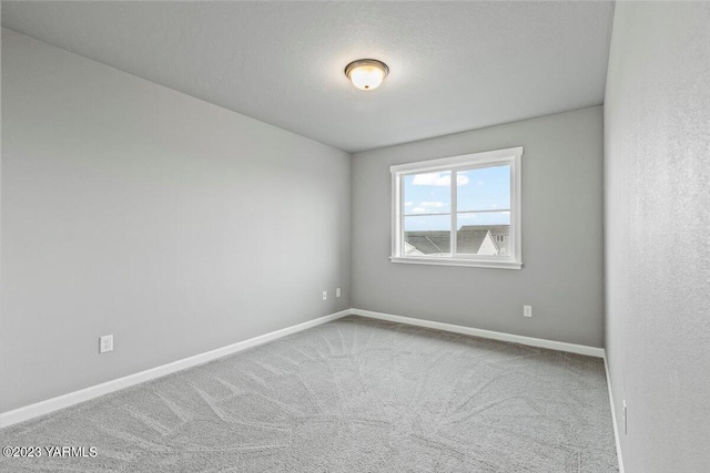 carpeted empty room featuring baseboards and a textured ceiling