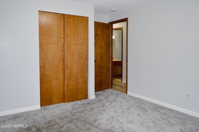 unfurnished bedroom with baseboards, a closet, carpet floors, and a textured ceiling