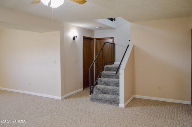 stairway with baseboards, carpet flooring, ceiling fan, and a textured ceiling