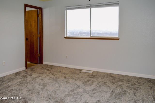 carpeted empty room featuring baseboards