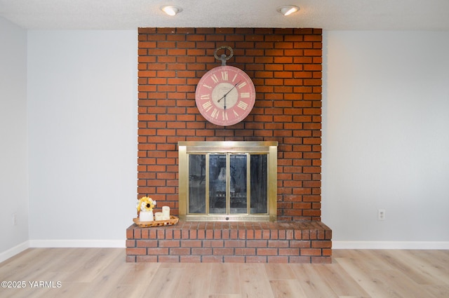 room details featuring baseboards, a fireplace, and wood finished floors