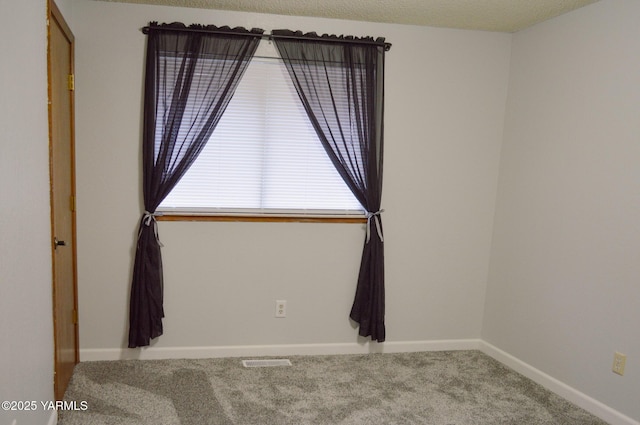 empty room featuring baseboards, visible vents, and carpet