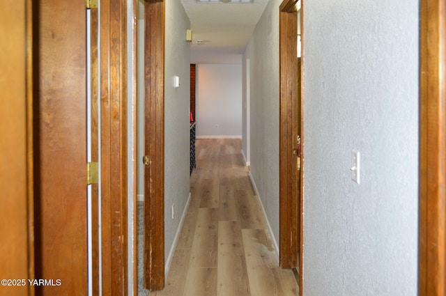 hallway with baseboards and light wood-style floors