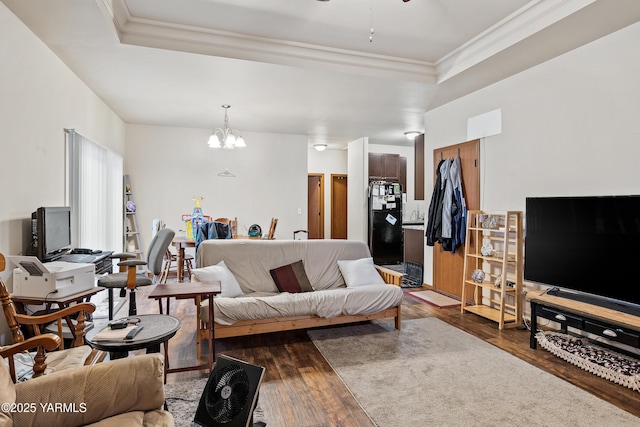 living area with dark wood-style floors, ceiling fan with notable chandelier, a raised ceiling, and crown molding