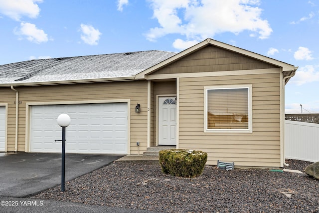 view of front facade with a garage, driveway, and fence