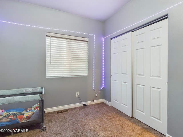 unfurnished bedroom with a closet, carpet flooring, visible vents, and baseboards