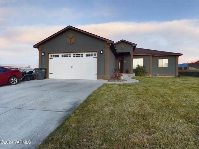 single story home featuring a yard, concrete driveway, an attached garage, and stucco siding