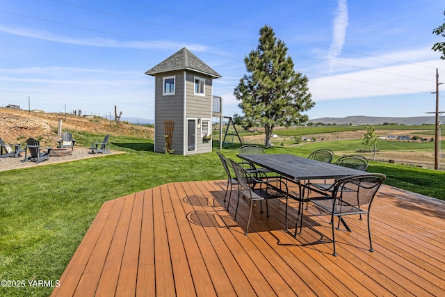 12826 Douglas Rd, Yakima, WA 98908 - wooden deck with an outdoor fire pit, outdoor dining space, a yard, a mountain view, and an outbuilding