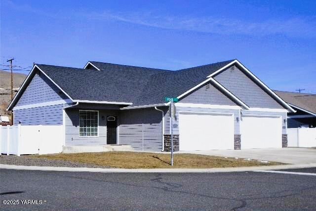 view of front of property with fence, an attached garage, concrete driveway, and stone siding