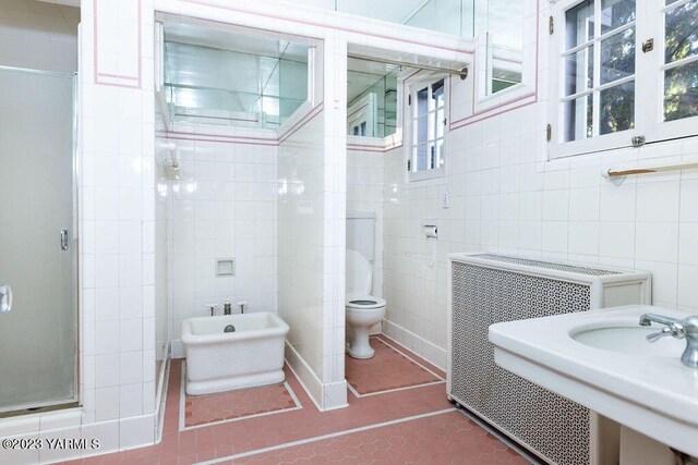 full bathroom with a stall shower, toilet, tile patterned flooring, a bidet, and tile walls