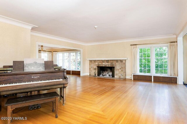 living room with radiator heating unit, a tiled fireplace, a wealth of natural light, and crown molding