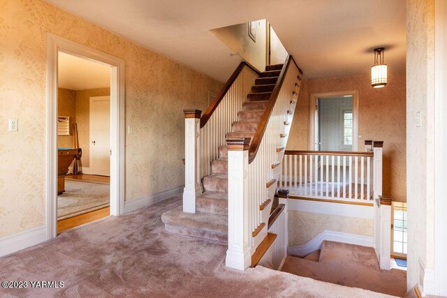 stairway with carpet flooring, baseboards, and wallpapered walls