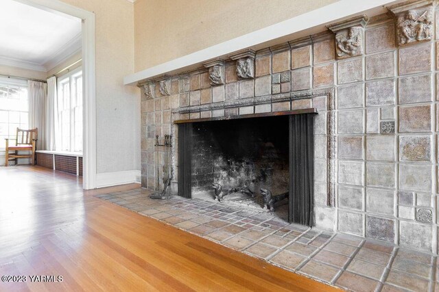 details with baseboards, radiator, wood finished floors, crown molding, and a brick fireplace