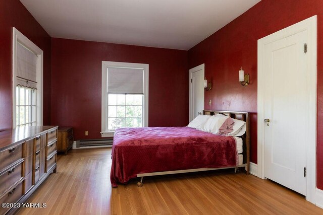 bedroom featuring light wood-style floors and a baseboard radiator