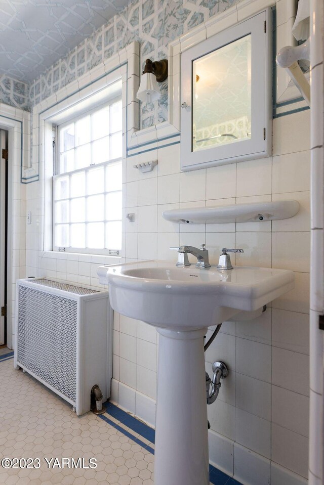 bathroom with radiator heating unit, tile walls, and wallpapered walls