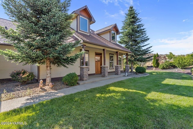 view of front of property with covered porch, roof with shingles, and a front yard