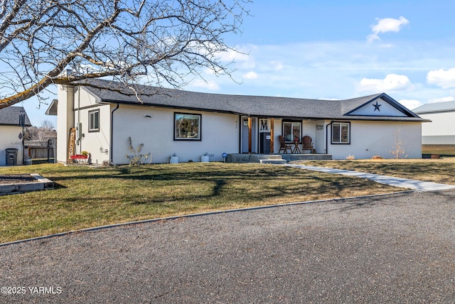 ranch-style home with stucco siding, covered porch, and a front yard