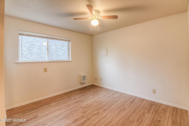 spare room with ceiling fan, light wood-style flooring, baseboards, and a textured ceiling