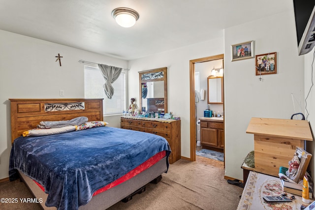 bedroom featuring baseboards, light colored carpet, and ensuite bathroom