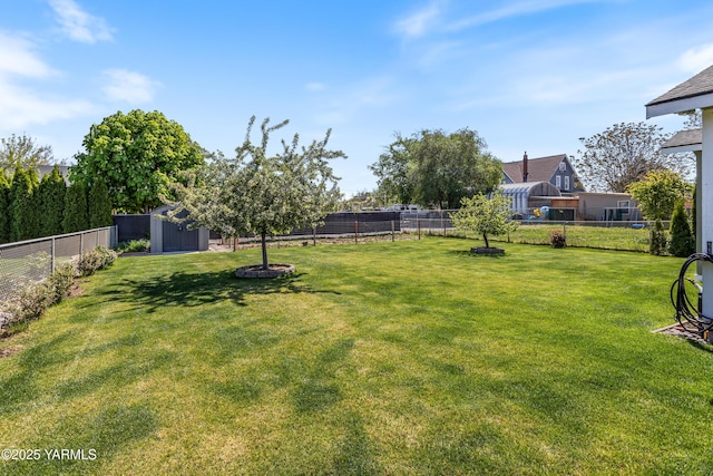 view of yard featuring an outdoor structure, a fenced backyard, and a storage shed