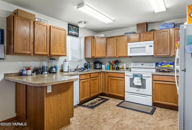 kitchen featuring a sink, white appliances, light countertops, brown cabinetry, and a peninsula